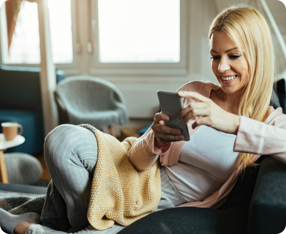 Χαρούμενο άτομο χρησιμοποιεί κινητό τηλέφωνο ενώ κάθεται σε καναπέ