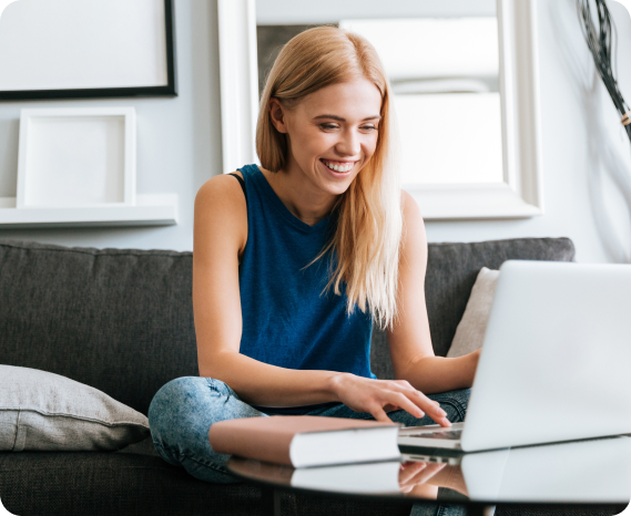 Χαρούμενο άτομο κάθεται σε καναπέ και χρησιμοποιεί laptop